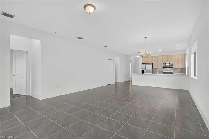 Unfurnished living room with dark tile patterned floors, recessed lighting, and a chandelier