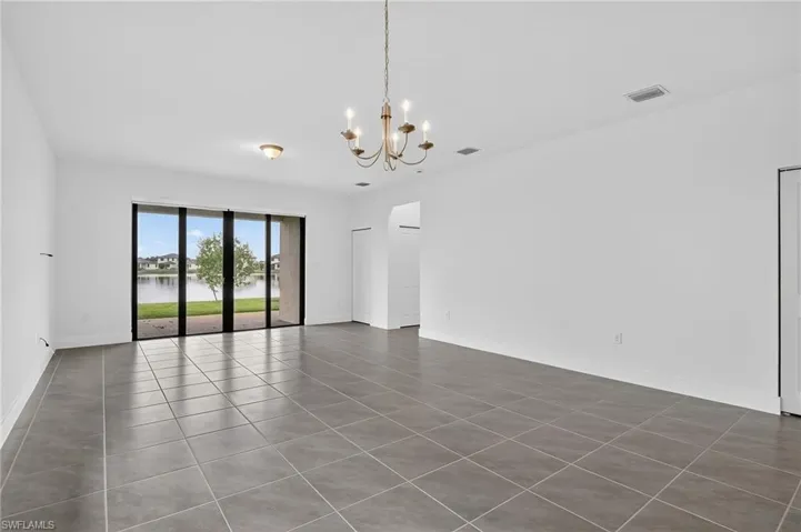 Tiled empty room featuring a water view and a chandelier