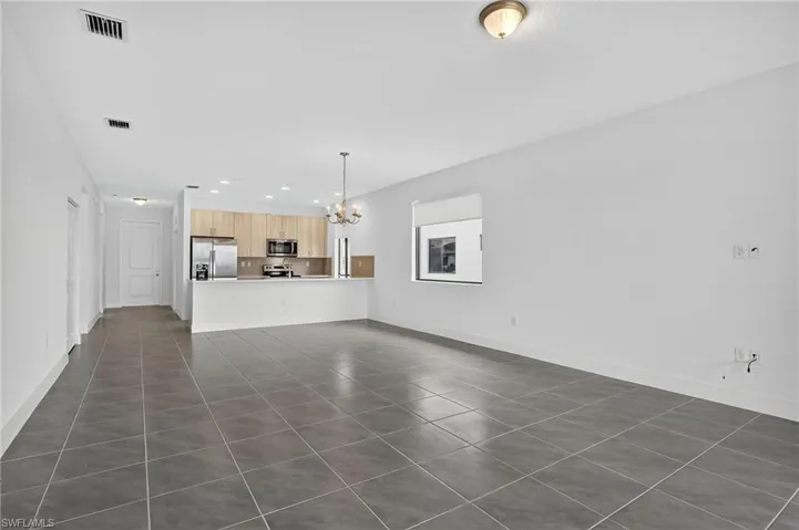 Unfurnished living room with dark tile patterned floors, a chandelier, and recessed lighting