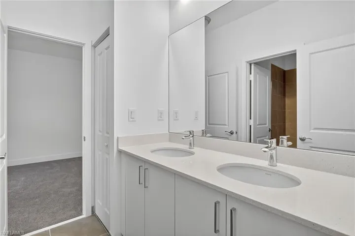 Full bathroom with double vanity and light tile patterned floors
