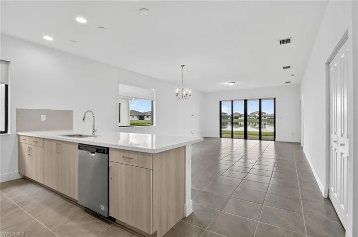 Kitchen featuring light brown cabinetry, healthy amount of natural light, a peninsula, light tile patterned floors, and recessed lighting