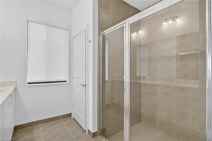 Bathroom featuring vanity, a shower stall, and light tile patterned floors