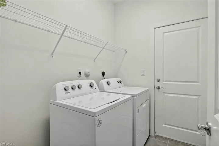 Washroom with tile patterned flooring and washer and dryer