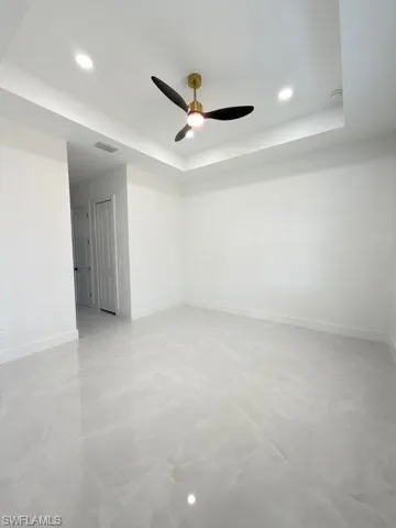 Empty room featuring recessed lighting, a tray ceiling, and a ceiling fan