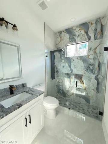 Full bath featuring vanity and a marble finish shower