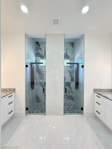 Bathroom with vanity, a marble finish shower, recessed lighting, and light marble finish flooring