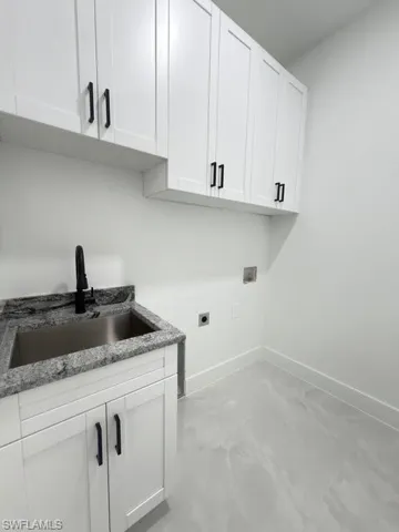 Laundry room with hookup for an electric dryer, finished concrete floors, cabinet space, and hookup for a washing machine
