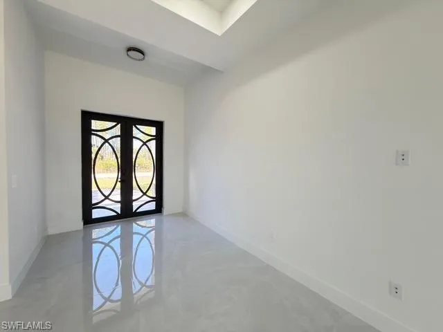 Spare room featuring french doors and concrete floors