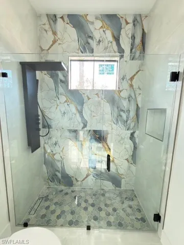 Full bathroom with a marble finish shower