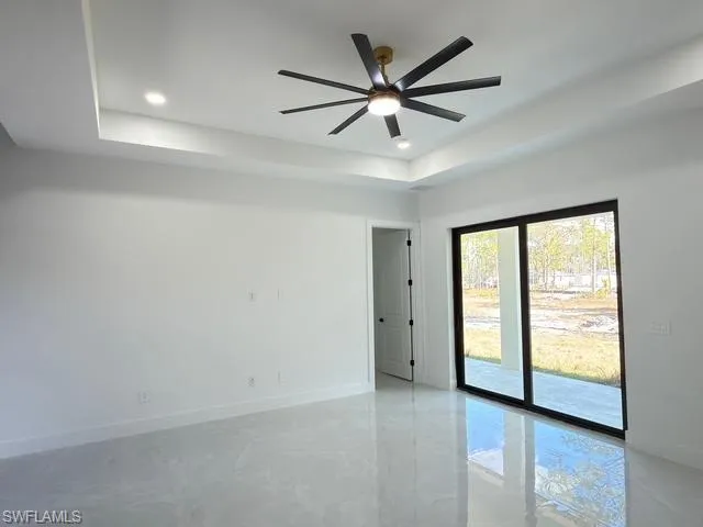 Empty room with a tray ceiling, recessed lighting, a ceiling fan, and finished concrete flooring