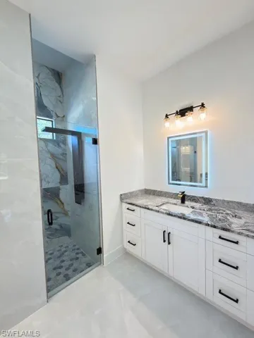 Bathroom featuring vanity and a marble finish shower