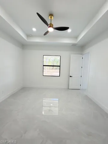 Empty room featuring a tray ceiling, a ceiling fan, and recessed lighting