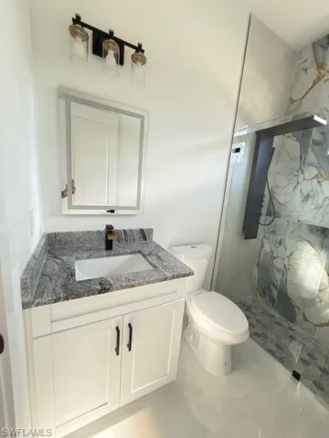 Full bath featuring vanity and a marble finish shower