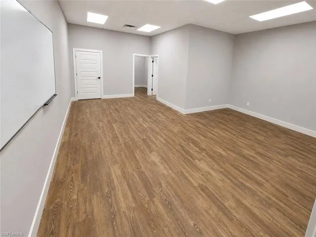 Spacious room featuring wood-finish flooring and light gray walls