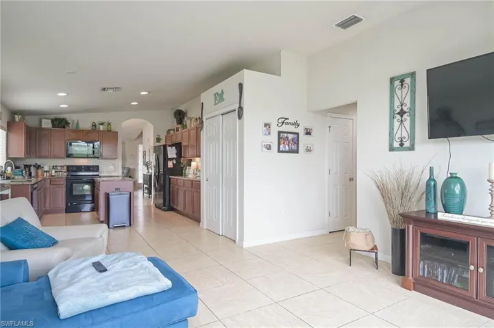 Living room featuring light tile patterned floors, vaulted ceiling, and sink