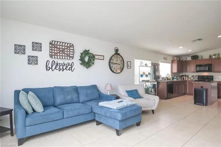 Living room with light tile patterned flooring, vaulted ceiling, and sink