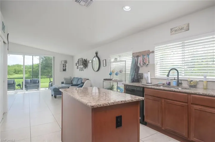 Kitchen featuring light stone countertops, light tile patterned floors, sink, a center island, and lofted ceiling