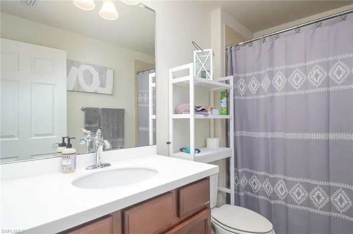 Bathroom featuring a shower with curtain, vanity, and toilet