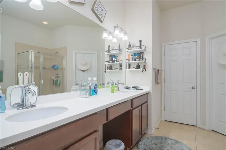 Bathroom featuring tile patterned flooring, walk in shower, and vanity