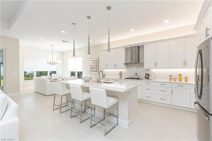 Kitchen featuring white cabinetry, sink, wall chimney range hood, and stainless steel appliances