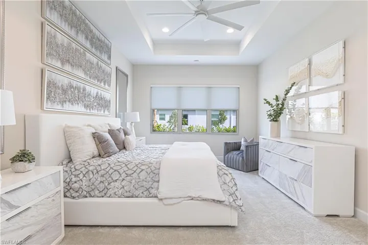 Bedroom featuring a tray ceiling, ceiling fan, and light colored carpet