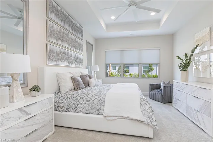 Carpeted bedroom with ceiling fan and a raised ceiling