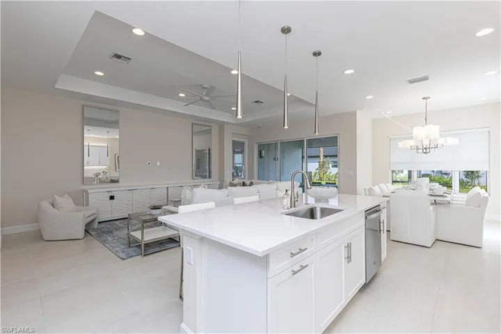 Kitchen featuring white cabinets, a center island with sink, a healthy amount of sunlight, and sink