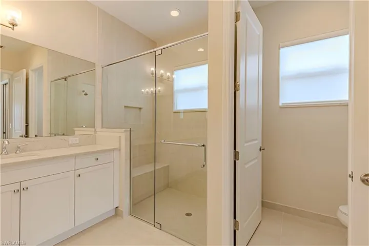 Bathroom with vanity, toilet, tile patterned floors, and a shower with door