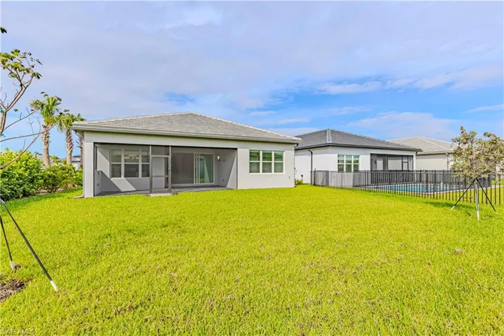 Back of house with a swimming pool, a sunroom, and a lawn
