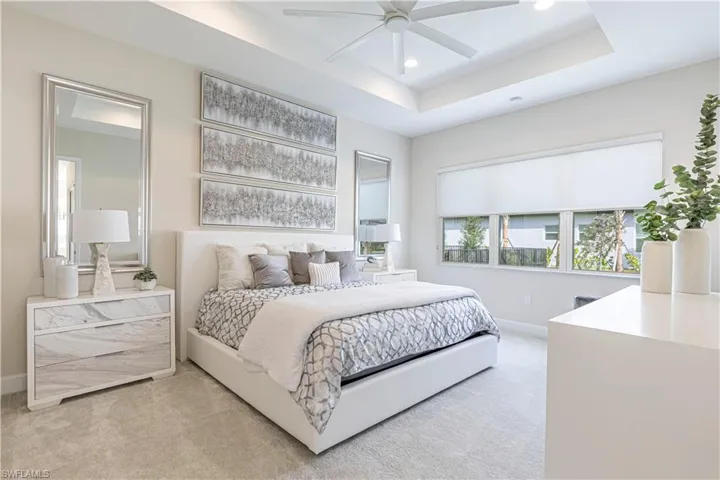 Carpeted bedroom featuring ceiling fan and a raised ceiling