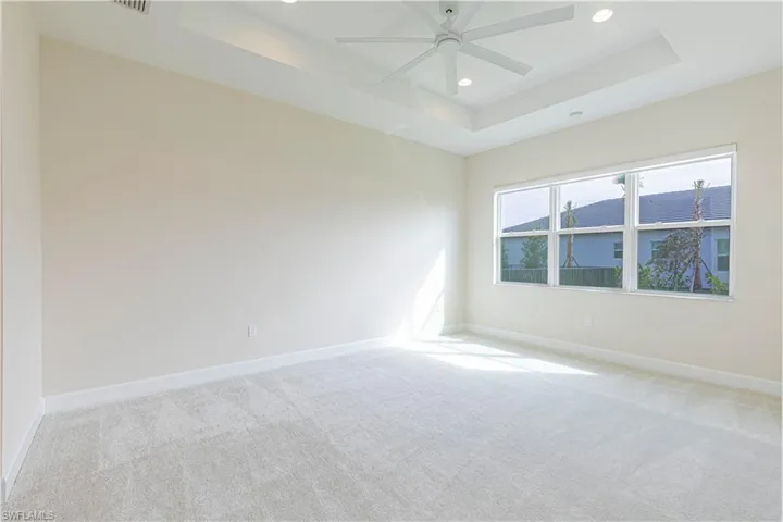 Spare room with ceiling fan, light colored carpet, and a raised ceiling