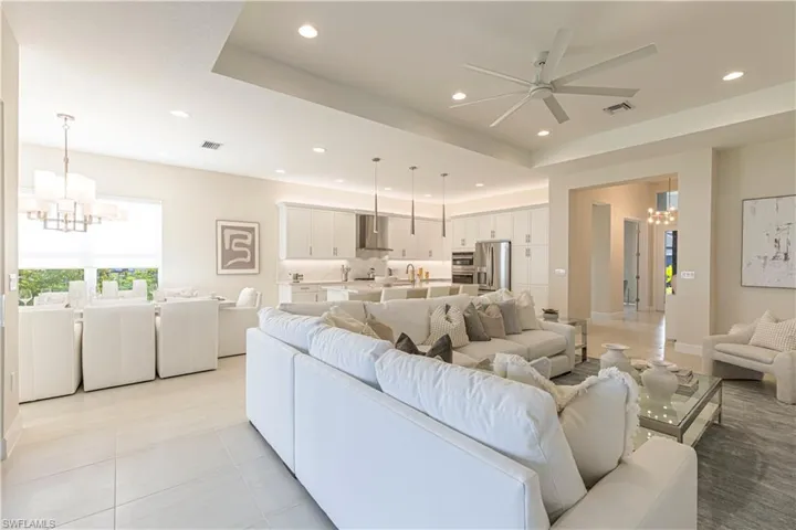 Tiled living room featuring ceiling fan with notable chandelier, washer / dryer, and sink