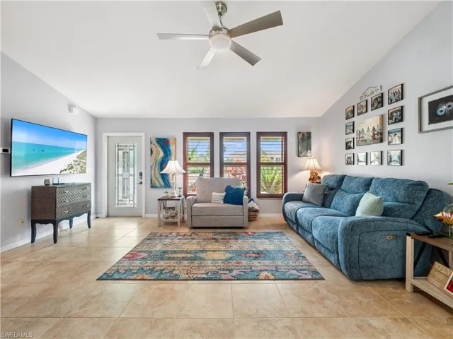 Living area featuring a ceiling fan, lofted ceiling, and light tile patterned floors