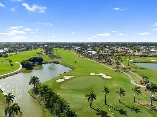 Aerial view of residential area featuring a golf course and a nearby body of water