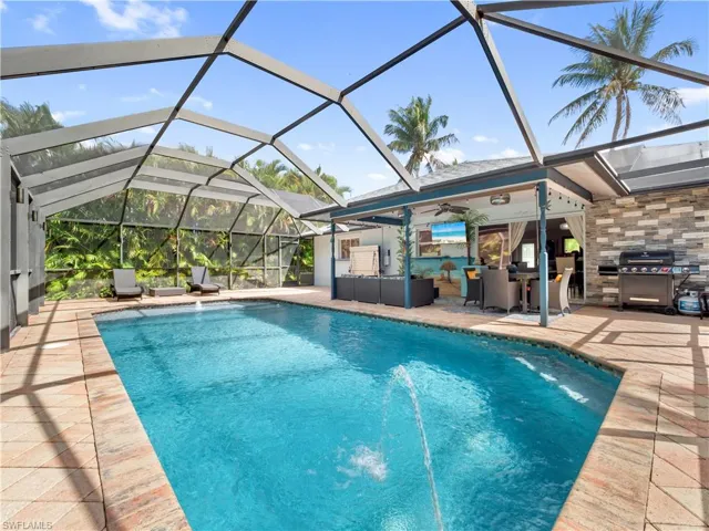 Outdoor pool featuring a grill, glass enclosure, a patio, and a sunroom