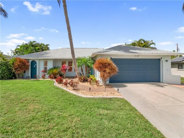 Ranch-style house with stucco siding, driveway, a garage, a front lawn, and roof with shingles