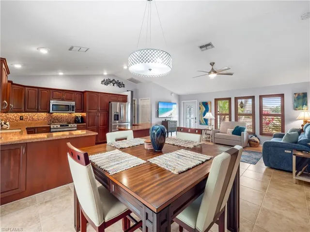 Dining area with vaulted ceiling, a ceiling fan, and light tile patterned floors