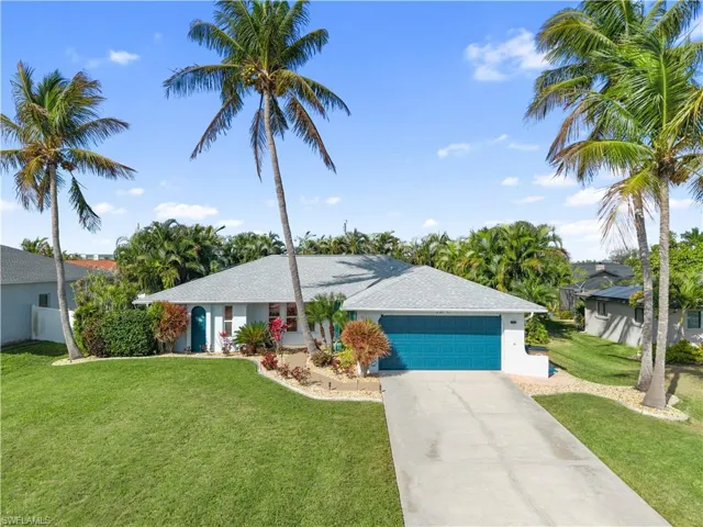 Ranch-style home featuring a front yard, an attached garage, driveway, stucco siding, and roof with shingles