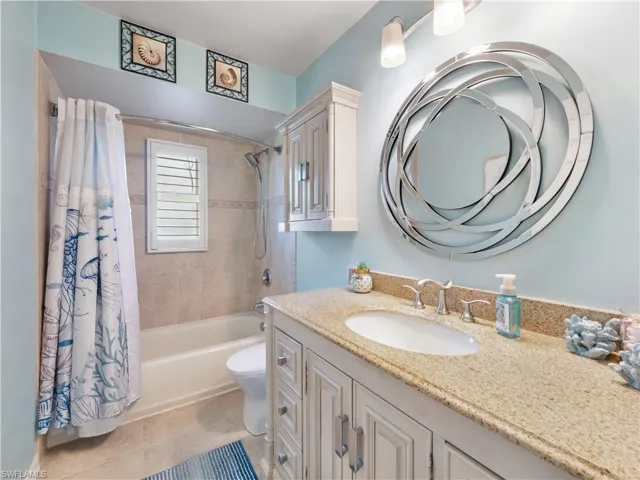Full bath featuring vanity, light tile patterned floors, and shower / tub combo with curtain