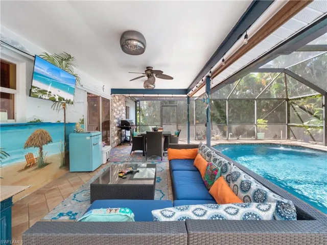 Swimming pool featuring a sunroom, an outdoor living / dining area, a grill, a patio, and a lanai