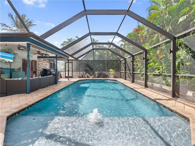 Swimming pool featuring glass enclosure, outdoor seating, a sunroom, and a patio area