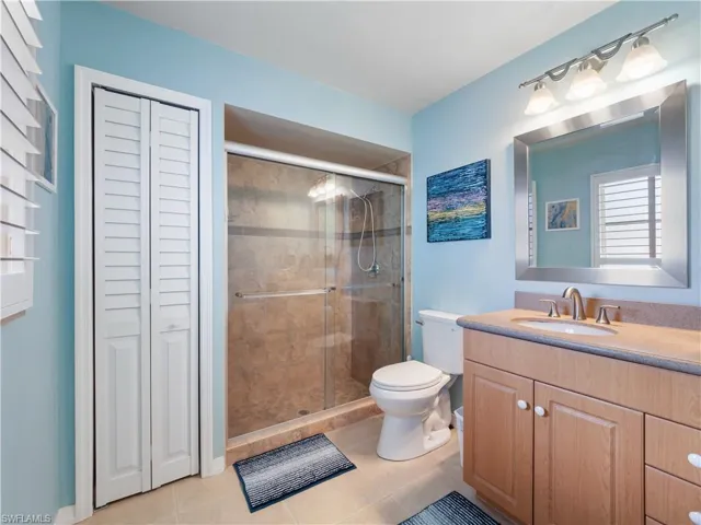 Full bathroom featuring a closet, vanity, light tile patterned floors, and a stall shower