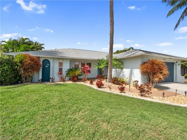 Ranch-style house featuring stucco siding, a front lawn, an attached garage, and concrete driveway