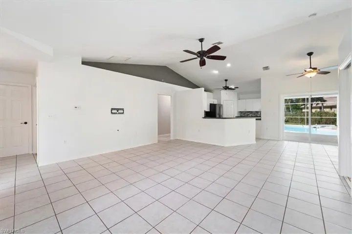 Unfurnished living room featuring lofted ceiling, light tile patterned floors, recessed lighting, and a ceiling fan