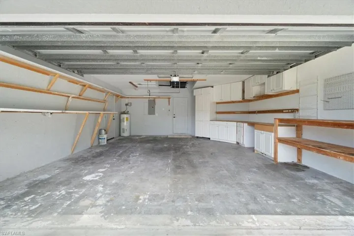 Garage featuring electric panel and electric water heater