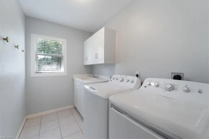 Laundry room featuring light tile patterned floors, washer and dryer, and cabinet space