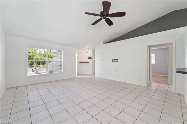 Unfurnished room featuring vaulted ceiling, light tile patterned floors, and a ceiling fan