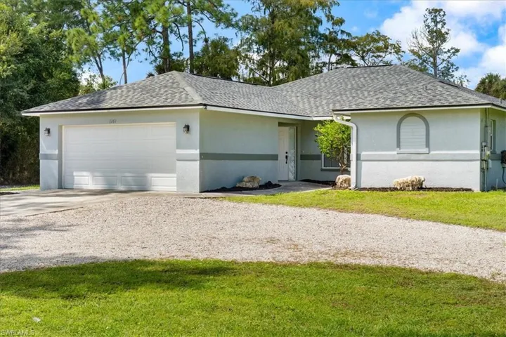 Ranch-style house with a shingled roof, stucco siding, driveway, and a garage
