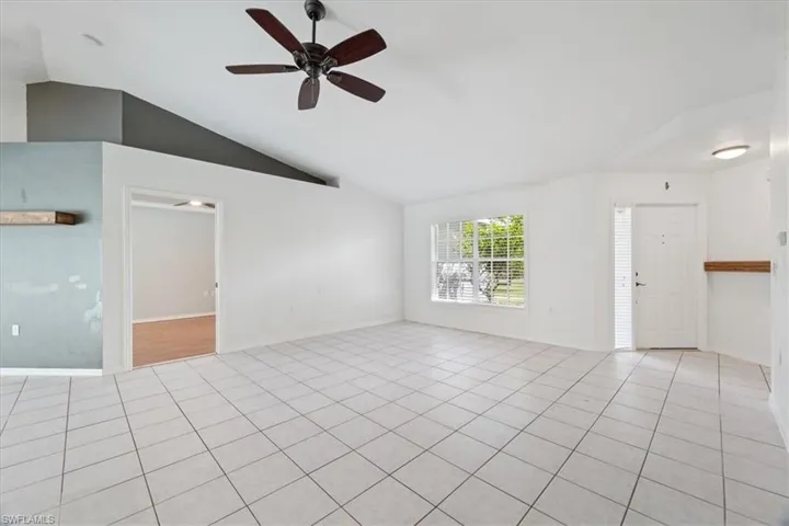 Unfurnished room featuring vaulted ceiling, light tile patterned floors, and a ceiling fan
