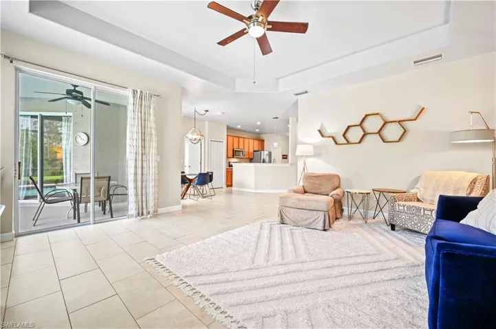 Living room with a tray ceiling, ceiling fan, and light tile floors